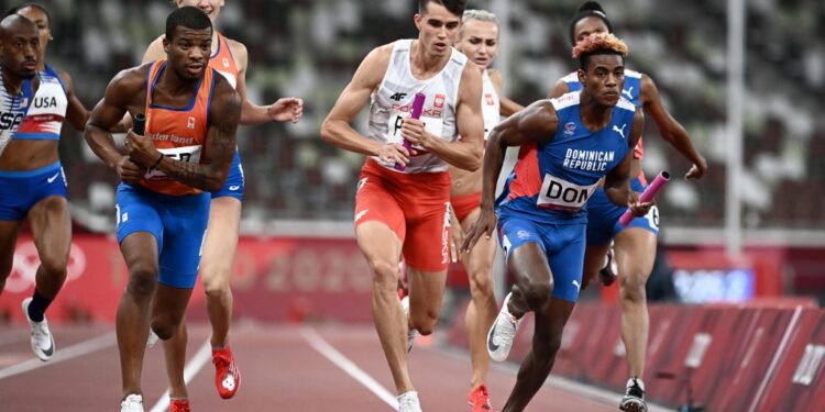 Netherlands' Ramsey Angela (L), Poland's Kajetan Duszynski (C) and Dominican Republic's Alexander Ogando Bautista compete in  the mixed 4x400m relay final during the Tokyo 2020 Olympic Games at the Olympic Stadium in Tokyo on July 31, 2021. (Photo by Jewel SAMAD /