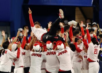 Japan's head coach Reika Utsugi (top C) is tossed in the air by her players after their victory in the Tokyo 2020 Olympic Games softball gold medal game between Japan and USA at the Yokohama Baseball Stadium in Yokohama, Japan, on July 27, 2021. (Photo by STR / JIJI PRESS / AFP) / Japan OUT